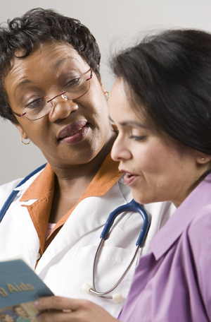 Mujer mirando un folleto de formación para pacientes junto con una proveedora de atención médica.