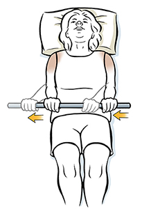 Una mujer acostada boca arriba que sostiene una vara hace un ejercicio de rotación externa del hombro.