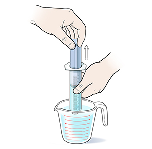 Primer plano de manos extrayendo agua con una jeringa a rosca de un vaso de medición.